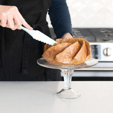 Nordic Ware serrated bundt tool cutting through golden-brown bundt cake with detailed ridged pattern