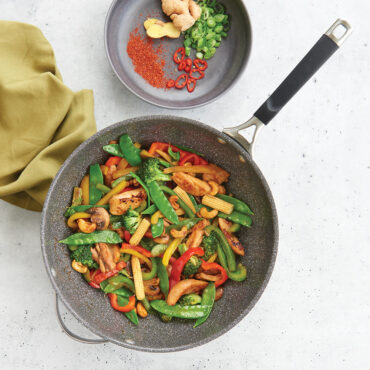 Nordic Ware Verde ceramic nonstick wok filled with colorful cooked stir fry vegetables and meat, overhead view