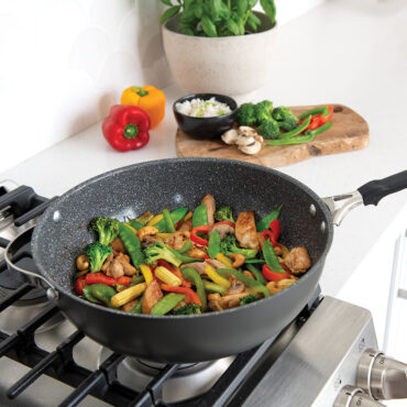 Nordic Ware Verde ceramic nonstick wok on stovetop with colorful stir-fried vegetables being cooked
