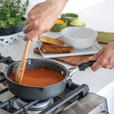 Nordic Ware Verde ceramic nonstick 8-inch skillet with green exterior cooking red tomato soup on stovetop