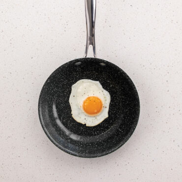Nordic Ware Basalt 8-inch sauté skillet with dark nonstick interior, cooking a fried egg with runny yolk