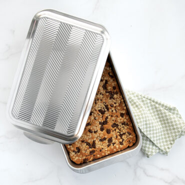 Baked chocolate chip cookie bars in Nordic Ware rectangular aluminum pan with geometric embossed lid