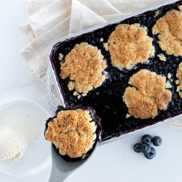 Berry cobbler being served with spatula from Nordic Ware ProCast aluminum 7x11 baking pan, golden-brown dessert