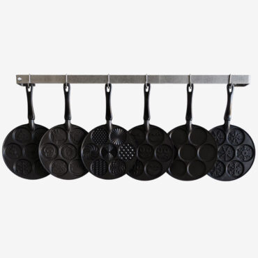 Five Nordic Ware aluminum pancake pans with different decorative patterns hanging on white wall display