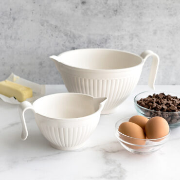 White Nordic Ware mixing bowls with pour spouts filled with flour, sugar, and baking ingredients on countertop