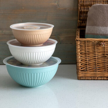 Nordic Ware covered bowls stacked with colorful prepared foods including salads and sides for outdoor dining