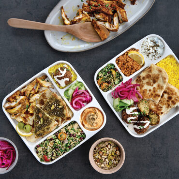 Two white plastic Nordic Ware divided meal trays with five compartments each, viewed from above