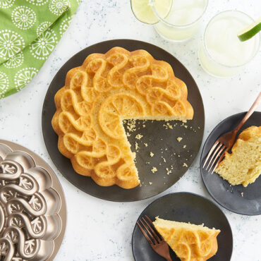 Sliced margarita cake with citrus twist pattern from Nordic Ware aluminum bundt pan, served with lime garnish and cocktails
