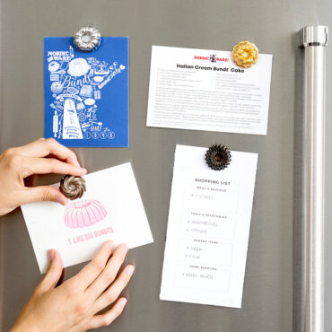 Hand placing colorful bundt-shaped magnet on white refrigerator, showing detailed fluted design
