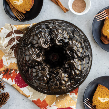 Nordic Ware Pumpkin Patch Bundt pan with golden baked cake showing detailed pumpkin-shaped design, surrounded by cake slices