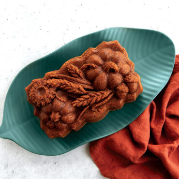 Sunflower Pumpkin Loaf Pan placed on a leaf-like green plate; concrete background