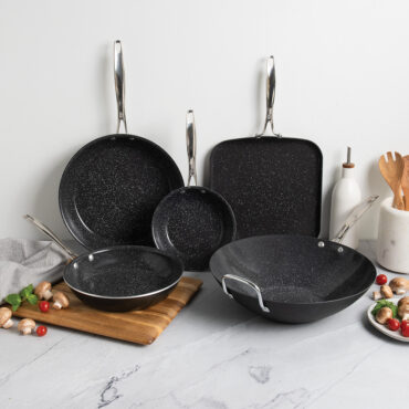 Nordic Ware Basalt 5-piece cookware set with dark non-stick interior displayed on kitchen counter with cooking ingredients