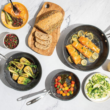 Nordic Ware Basalt 3-piece non-stick skillet set in charcoal gray with seared salmon, vegetables, and eggs