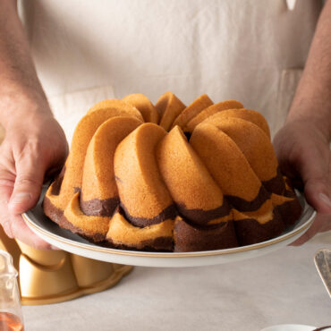Hands holding golden bundt cake with elegant twisted ridges baked in Nordic Ware Pirouette bundt pan