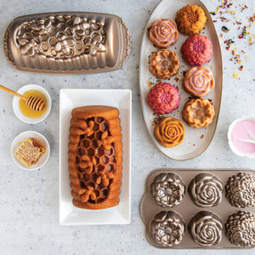 Six golden floral cakelets with white glaze on white plate, plus honey-glazed loaf cake from Nordic Ware pans