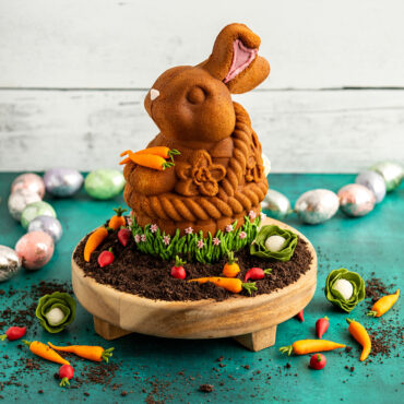 Nordic Ware aluminum 3D bunny in basket cake pan with golden-brown baked cake showing detailed bunny and woven basket texture