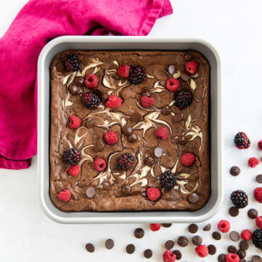 Nordic Ware Brilliant 9" square aluminum cake pan with marble cake topped with fresh raspberries and chocolate chips