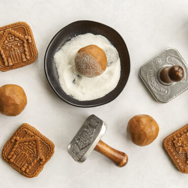Nordic Ware wooden gingerbread cookie stamps with rolled dough balls, pressed cookies, and sugar bowl