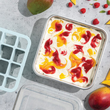 Nordic Ware brownie baking set with aluminum pan containing golden mango cheesecake bars, clear lid and cutting tool