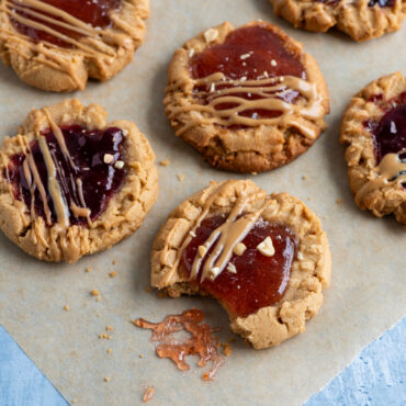 Freshly baked peanut butter and jelly cookies on parchment-lined Nordic Ware nonstick half sheet pan