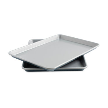 Two Nordic Ware aluminum half sheet pans with nonstick coating, stacked and angled, natural silver finish