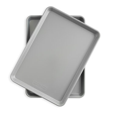 Two Nordic Ware nonstick half sheet pans stacked, rectangular aluminum baking sheets with dark coating
