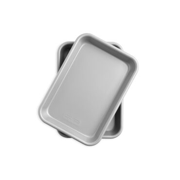 Two Nordic Ware nonstick eighth sheet pans stacked, rectangular aluminum baking pans with dark interior coating