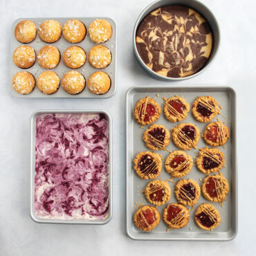 Nordic Ware nonstick baking set with three gray pans containing baked brownies, cookies, and muffins