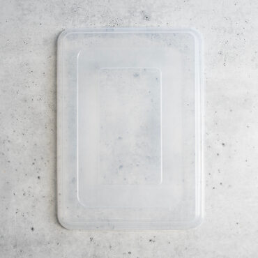 Nordic Ware clear plastic storage cover for big sheet pan, rectangular with raised edges on gray surface
