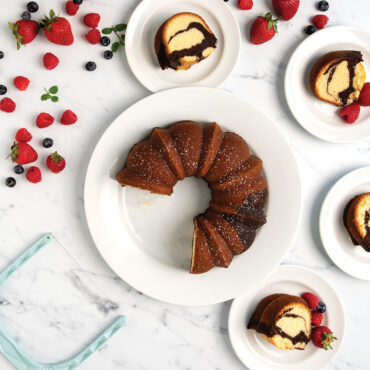 Nordic Ware bundt slicer tool beside chocolate bundt cake on white plate with perfectly cut slices displayed
