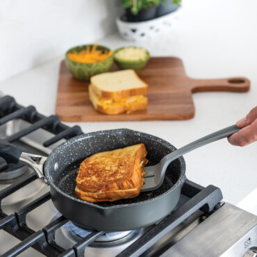 Nordic Ware Verde 8-inch ceramic nonstick skillet with lid cooking golden grilled cheese sandwich on stovetop
