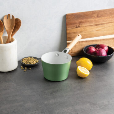 Nordic Ware 1.5-quart ceramic nonstick saucepan in warm cardamom color with long handle, styled with cooking ingredients