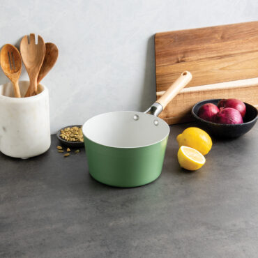 Nordic Ware 3-quart ceramic nonstick saucepan in cardamom color with lid, displayed with cooking ingredients