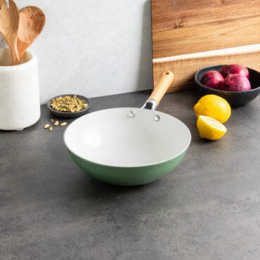 Nordic Ware 10-inch ceramic nonstick wok in cardamom green color with cooking ingredients and utensils