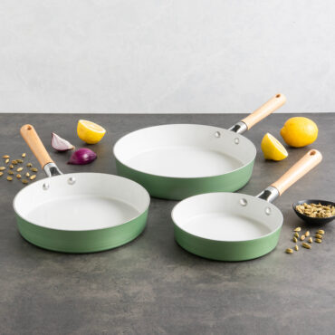 Nordic Ware Cardamom nonstick frying pan set with three gray pans and colorful spices on marble countertop