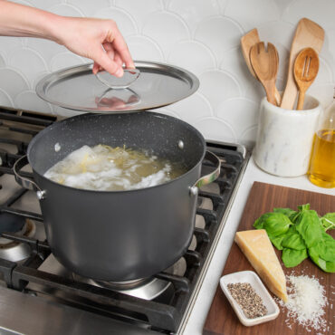 8qt Stock Pot with Lid on stovetop with boiling spaghetti; hand holding lid