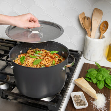 8qt Stock Pot with Lid on stovetop with spaghetti; hand holding lid