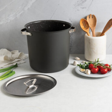Nordic Ware Verde 12-quart green non-stick stock pot with lid, styled with fresh tomatoes and wooden utensils