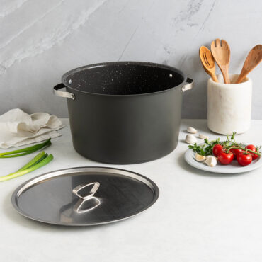 Nordic Ware Verde green ceramic-coated 16-quart stockpot with lid, styled with fresh tomatoes and wooden utensils