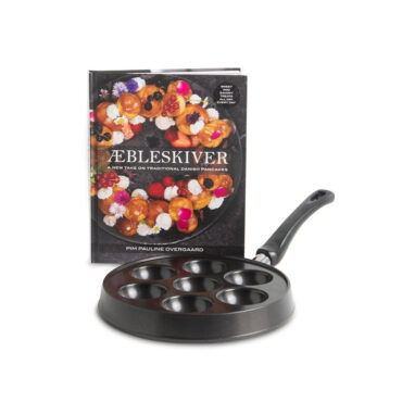 Nordic Ware cast aluminum ebelskiver pan with seven round wells and accompanying cookbook on white background