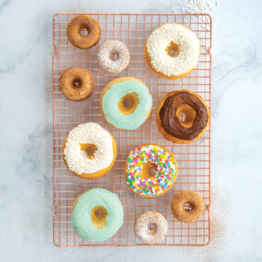 Assorted glazed and powdered donuts from Nordic Ware classic donut pan cooling on wire rack overhead view