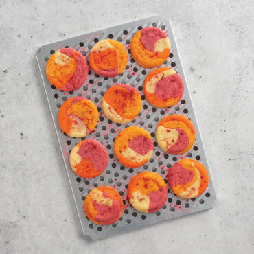 Wire cooling rack with golden baked sugar cookies, positioned over Nordic Ware aluminum half sheet pan
