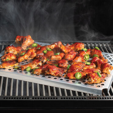 Nordic Ware aluminum cooling rack on outdoor grill with golden-brown grilled chicken pieces