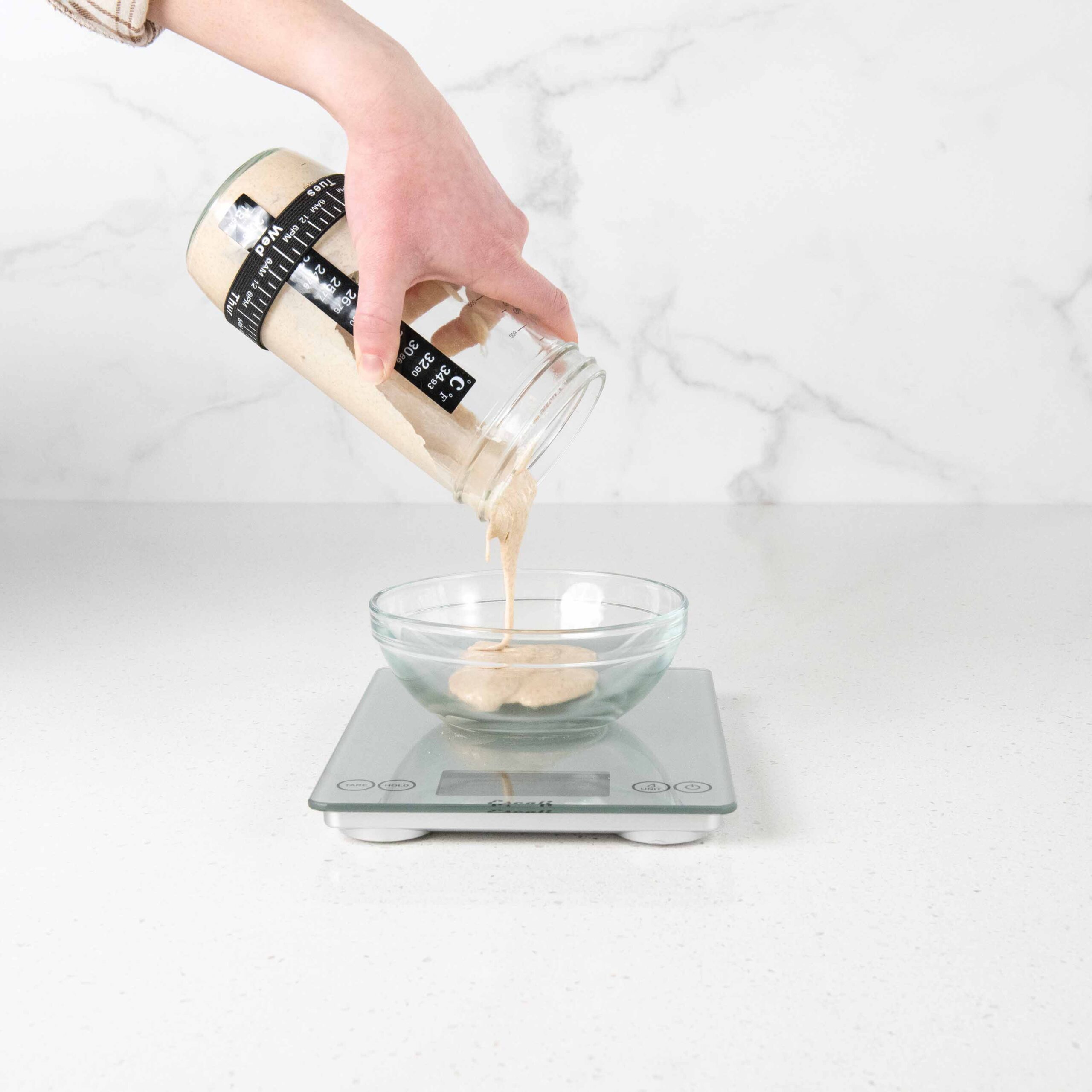 View of starter in jar getting poured into a small bowl