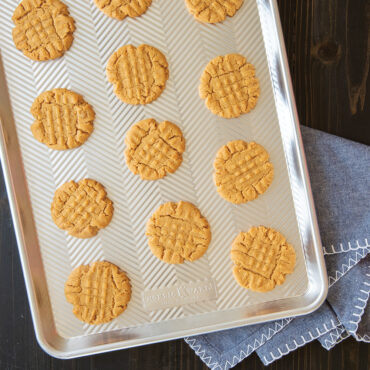 Golden baked peanut butter cookies arranged on Nordic Ware Prism aluminum half sheet pan with raised edges