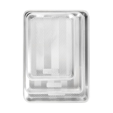 Three Nordic Ware aluminum baking sheets in graduated sizes with natural finish and raised edges