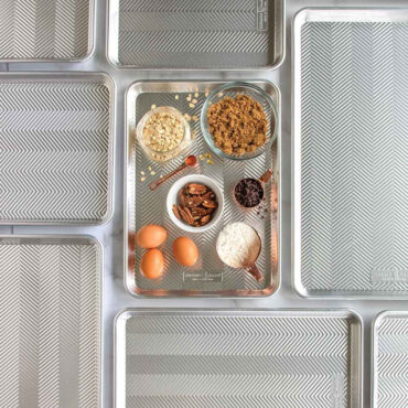 Nordic Ware Prism aluminum baking sheets with raw cookie dough, flour, and baking ingredients arranged overhead