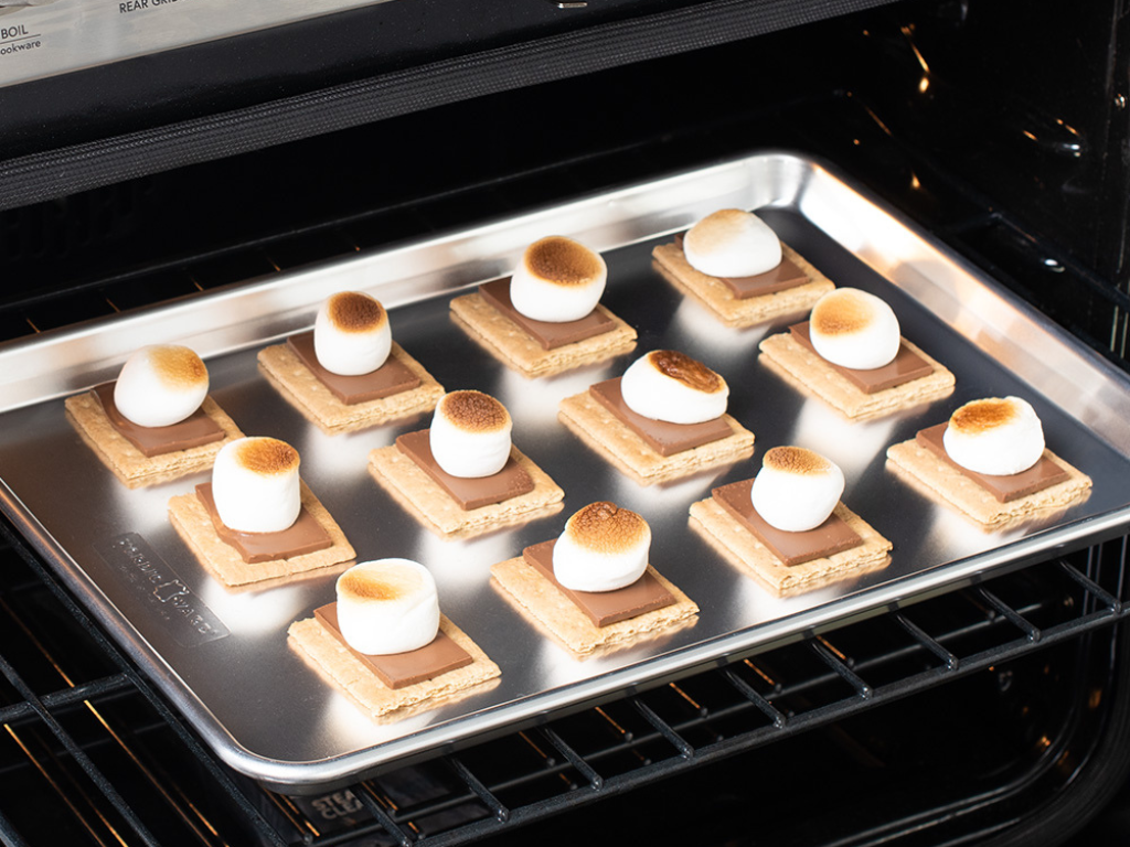 Baked and toasted smores on a baking sheet in the oven.