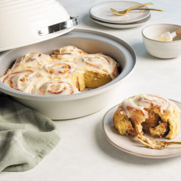 Baked cinnamon rolls in Nordic Ware Bread Baking Pan with one on a plate with a fork