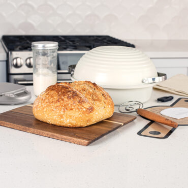 Nordic Ware sourdough bread baking kit with sliced artisan bread loaf, proofing baskets, and baking tools arranged on counter
